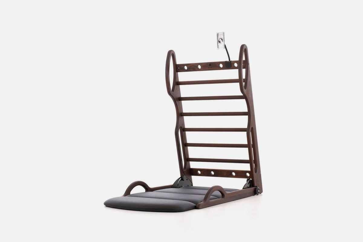 Open stretch station in dark brown wood with horizontal rungs and a dark fold-out mat