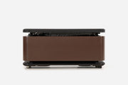 Front view of a dark reddish-brown storage bench with the padded lid raised and resistance bands visible inside